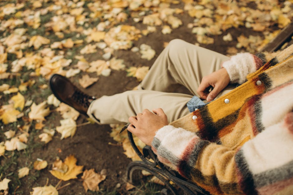 man layering clothes in city park autumn