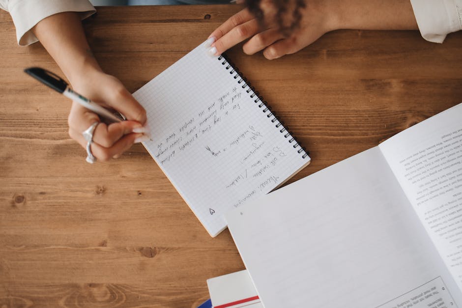 person writing notebook desk