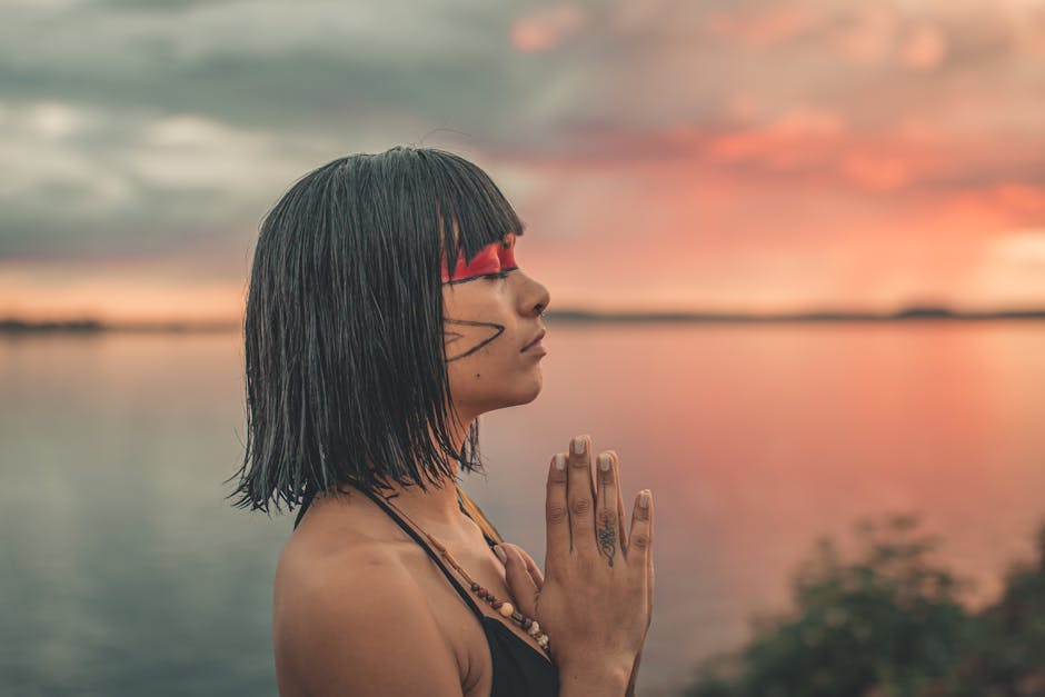 woman meditating by a lake at sunset