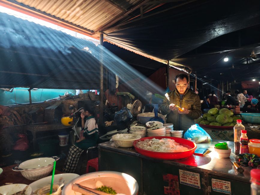 Mercato all'aperto con banchi di cibo locale e persone che passeggiano in un quartiere autentico