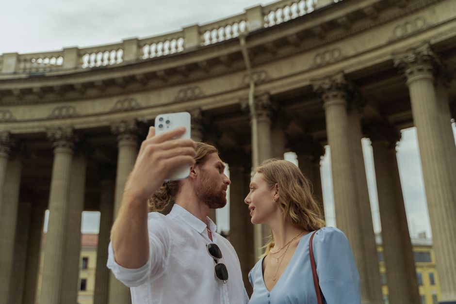 Una coppia sorride mentre esplora a piedi una strada storica in una città europea, godendosi un 'city break' post-lavoro.
