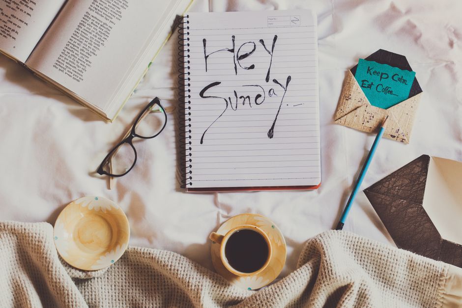 Una persona che legge un libro su un divano confortevole la domenica sera, con una coperta e una tazza di tè