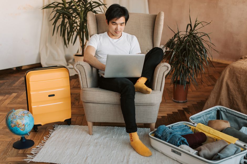 Nomade digitale che utilizza uno strumento AI su laptop per pianificare un viaggio, con una tazza di caffè e una mappa accanto