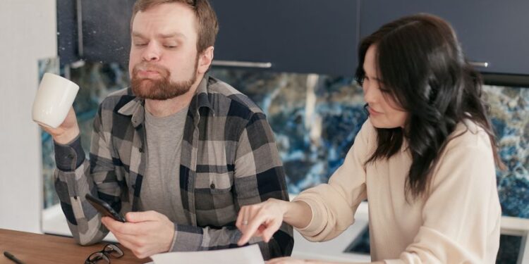 Famiglia italiana seduta al tavolo della cucina, che pianifica un budget mensile con quaderno e penne.