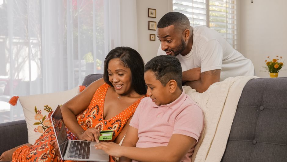 Famiglia che naviga su internet a casa, con un router Wi-Fi in evidenza e un cavo in fibra ottica.