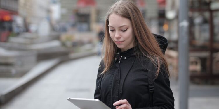 Famiglia italiana con bambini che usano un tablet connessi a Wi-Fi pubblico in un bar all'aperto, con un genitore che guarda lo schermo con preoccupazione.