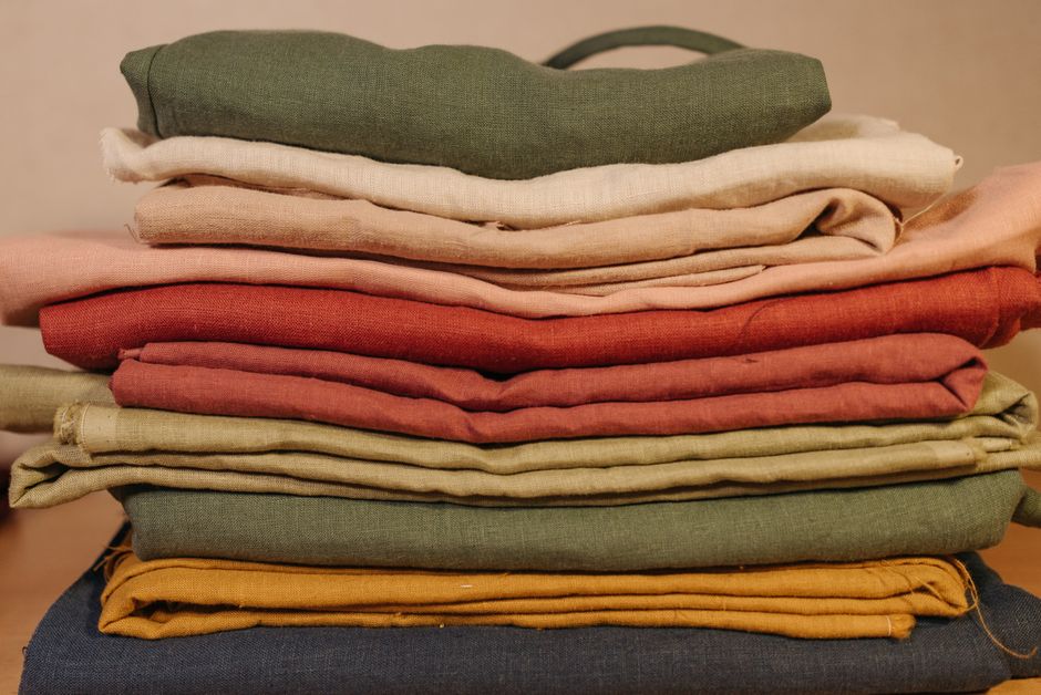 Abbigliamento leggero in lino e cotone appeso ad asciugare, con il sole sullo sfondo, simboleggiando il clima caldo.