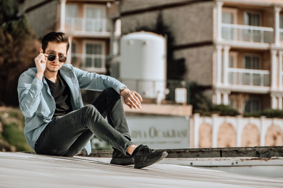 Мужчына ў джынсах slim-fit і кашулі стаіць у сучасным інтэр'еры, увасабляючы элегантны паўсядзённы вобраз.