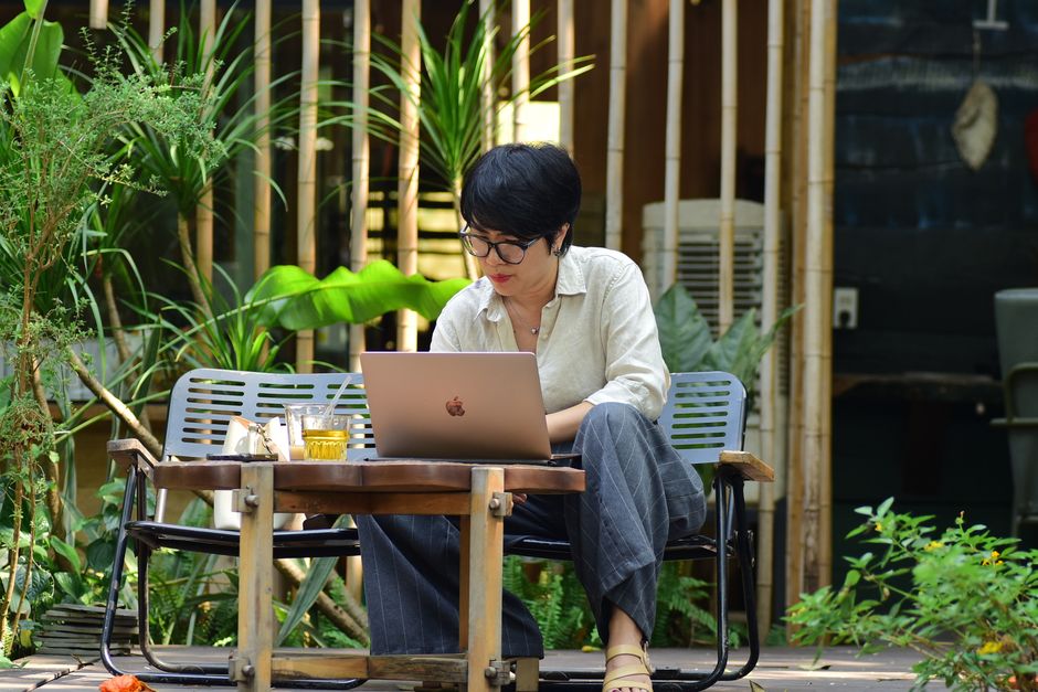 Un giovane professionista che lavora al laptop in un caffè accogliente, con una tazza di caffè e quaderni sparsi sul tavolo.