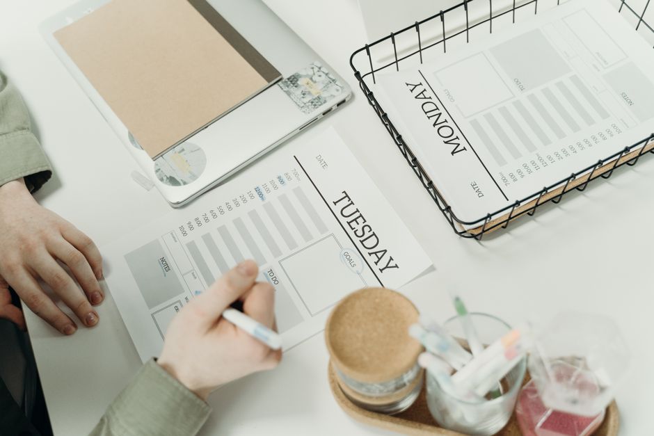 Una scrivania organizzata con un'agenda settimanale, una penna e una lista della spesa dettagliata per la pianificazione.