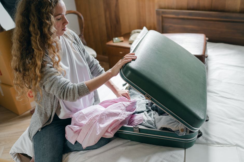 Una valigia ben organizzata con abiti a strati, tra cui una giacca impermeabile e scarpe robuste, che illustra il concetto di equipaggiamento versatile per ogni condizione climatica.