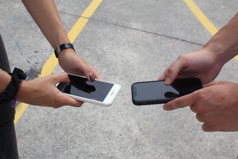 Gruppo di persone che confrontano diversi modelli di smartphone, discutendo le loro funzionalità AI e le performance.
