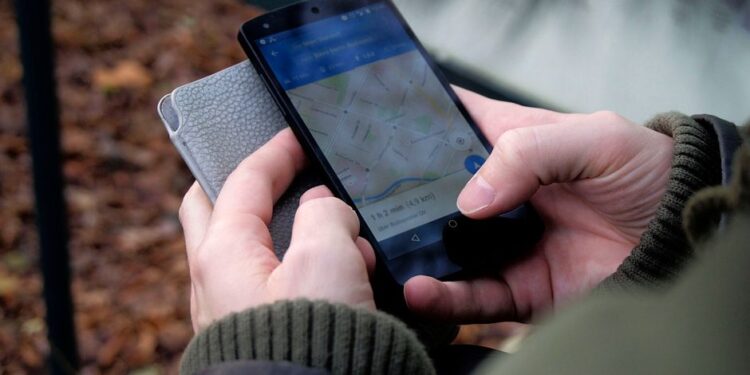 Una persona che controlla una mappa di copertura di rete sul suo smartphone in una città italiana, evidenziando la verifica della copertura mobile.