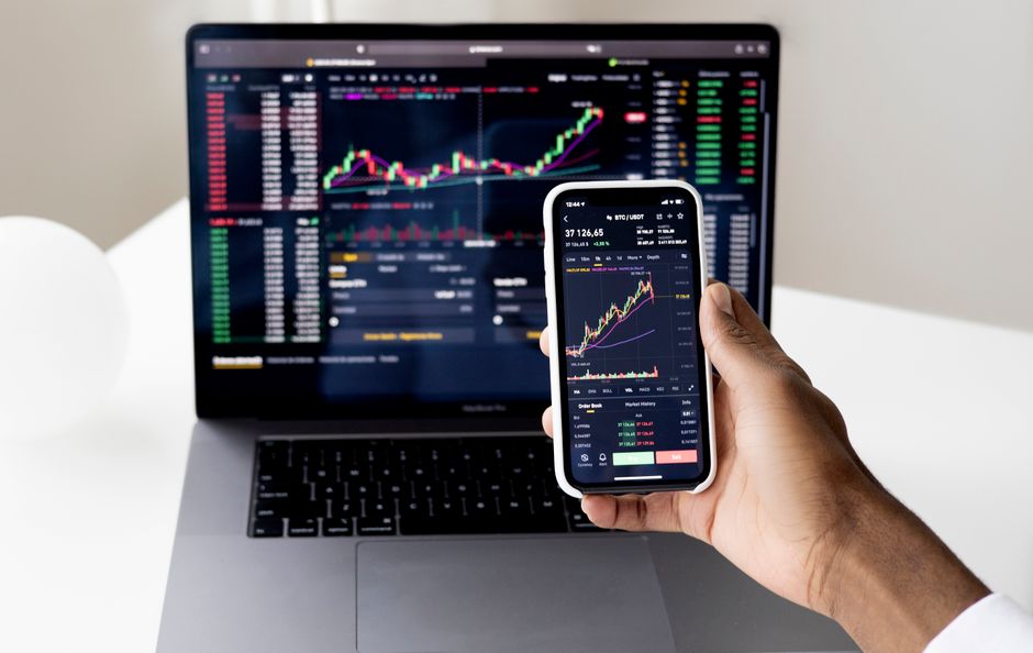 Muž porovnávající ceny smartphonů na notebooku s otevřenými různými záložkami e-shopů.
