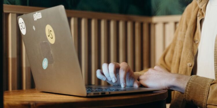 Persona che confronta le caratteristiche di diversi software AI su un laptop