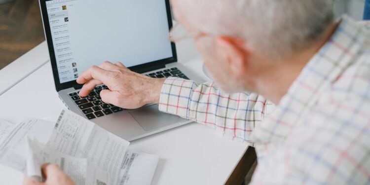 Una persona che controlla attentamente le informazioni generate dall'AI su un laptop, con libri aperti sullo sfondo, simboleggiando la verifica delle fonti.