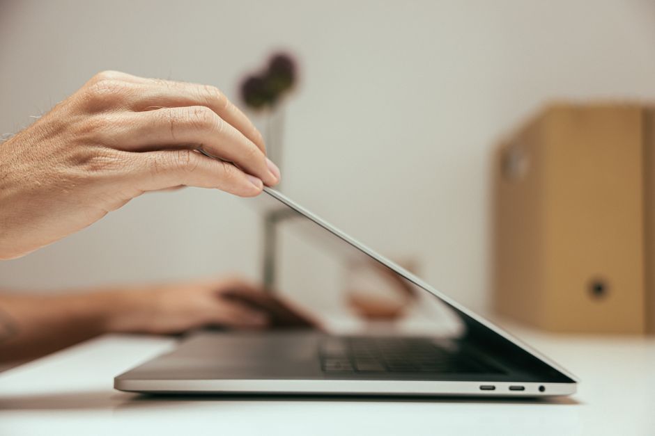 Una persona che chiude il laptop e lo ripone dopo l'orario di lavoro, con un'espressione di sollievo, simboleggiando la fine della giornata lavorativa e il rispetto dei confini digitali.