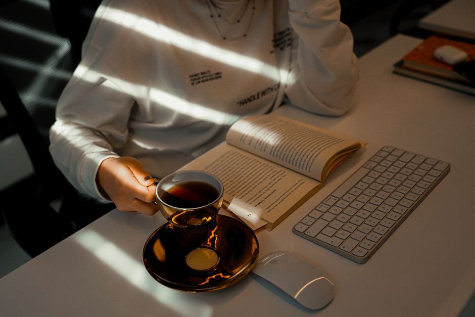 Дыстанцыйны работнік робіць перапынак на чытанне кнігі ў сваім хатнім офісе ў невялікай кватэры