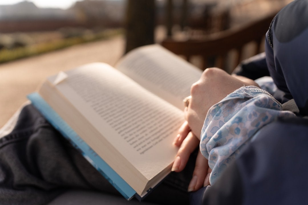 Persona seduta su una panchina in un parco tranquillo, immersa nella lettura di un libro, esempio di tempo libero di qualità.