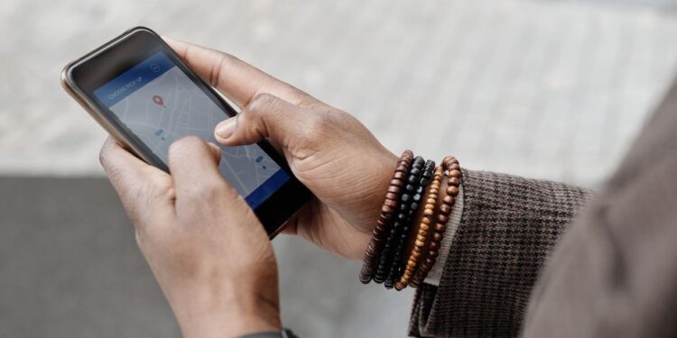 Persona che usa un'app di navigazione sullo smartphone mentre cammina in una piazza affollata di una città europea.