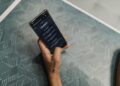 Чалавек карыстаецца смартфонам з AI-памочнікам, які адлюстроўвае прагноз надвор'я і маршрут.