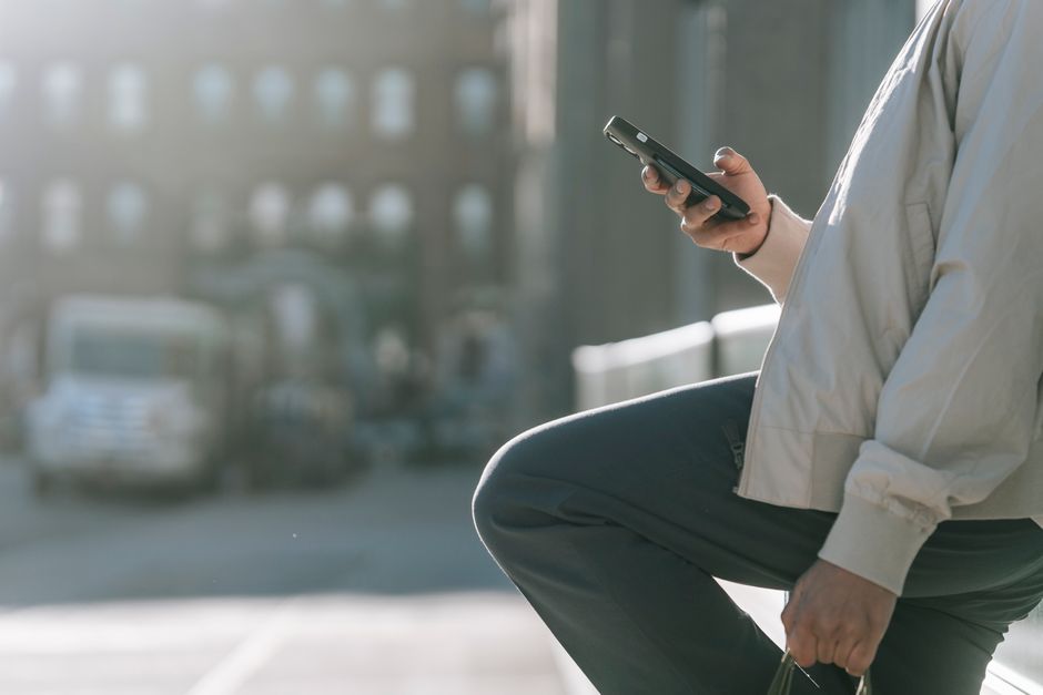 Una persona usa uno smartphone con funzionalità AI avanzate, come la fotografia intelligente, con uno sfondo urbano italiano