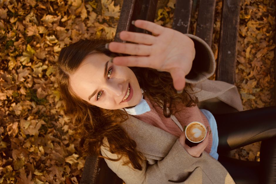 Una donna sorridente che rifiuta un caffè con un gesto gentile della mano.