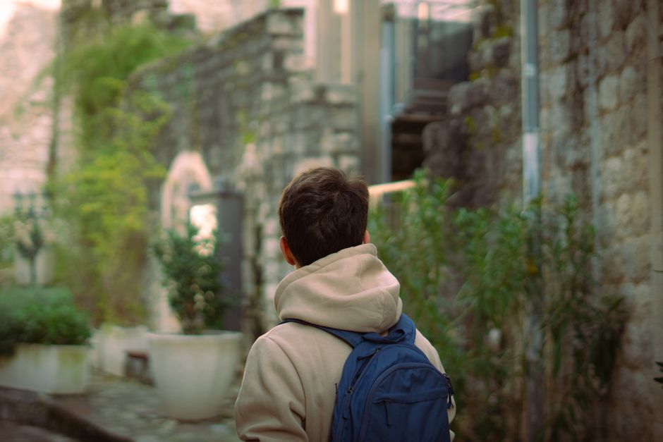 Viaggiatore solitario che esplora un vicolo pittoresco in una città storica europea, lontano dalla folla.