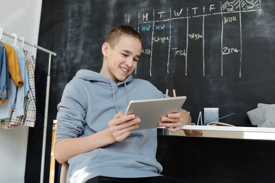 Uno studente concentrato che pianifica la sua sessione di studio su un tablet, utilizzando un'applicazione AI per ottimizzare il suo programma accademico.