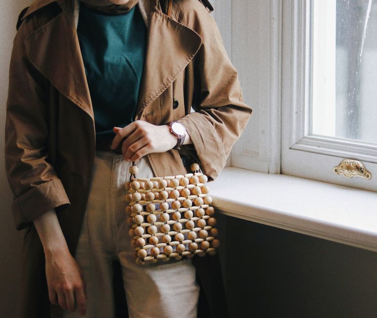 Una donna elegante che abbina un outfit base di colori neutri con una sciarpa di seta vivace e una borsa colorata, dimostrando la versatilità degli accessori.