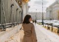 Стильна жінка йде брукованою вулицею європейського міста у зручних міських кедах