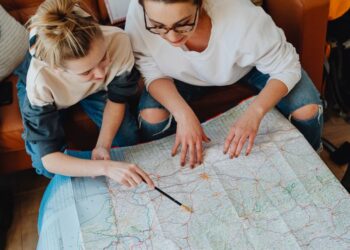 Una viaggiatrice solitaria consulta una mappa digitale su smartphone, con uno zaino da viaggio e un'espressione pensierosa.