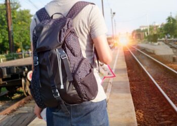 Viaggiatore consulta mappa e orari dei treni per pianificare un itinerario di viaggio a base unica.