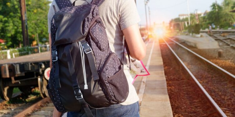 Viaggiatore consulta mappa e orari dei treni per pianificare un itinerario di viaggio a base unica.