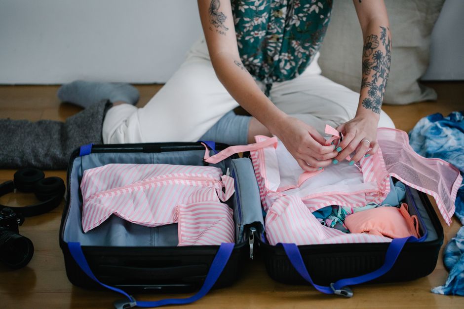 Un viaggiatore esperto che ripiega meticolosamente abiti versatili e anti-piega nella sua valigia, pronta per un viaggio con un guardaroba funzionale e leggero.