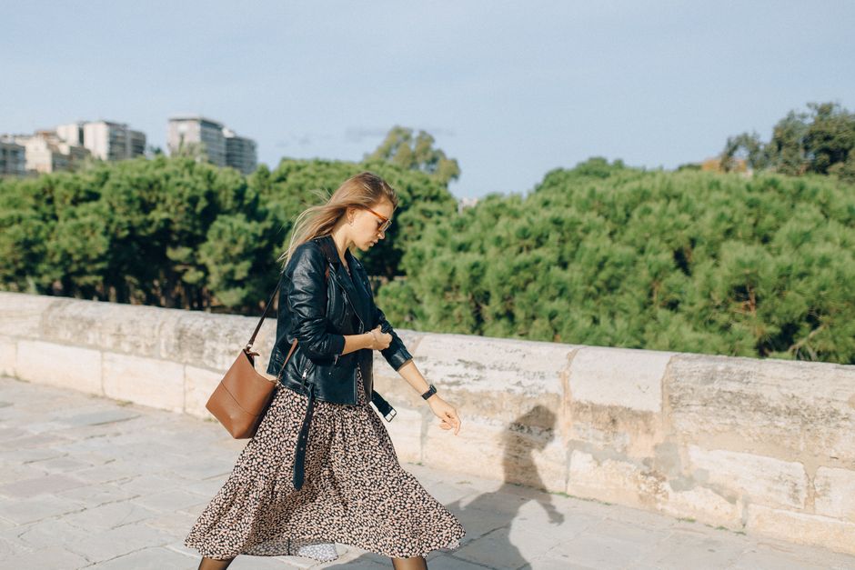Una viaggiatrice elegante con una borsa a tracolla di design italiano cammina su una strada acciottolata di una città storica europea