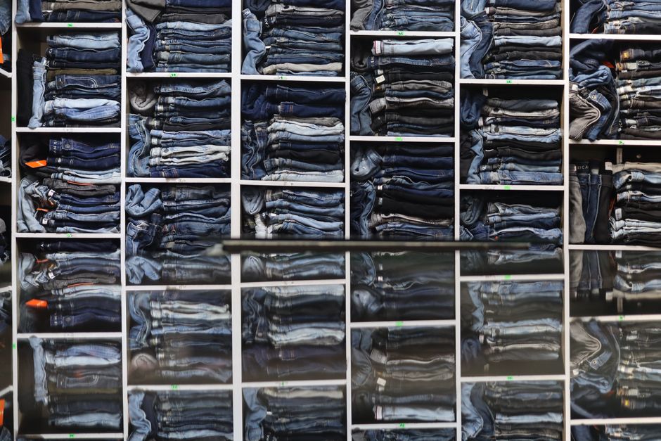 Una selezione di jeans con diversi lavaggi e tagli, dal più chiaro al più scuro, appesi ordinatamente in un guardaroba o in un negozio, mostrando la varietà del denim.