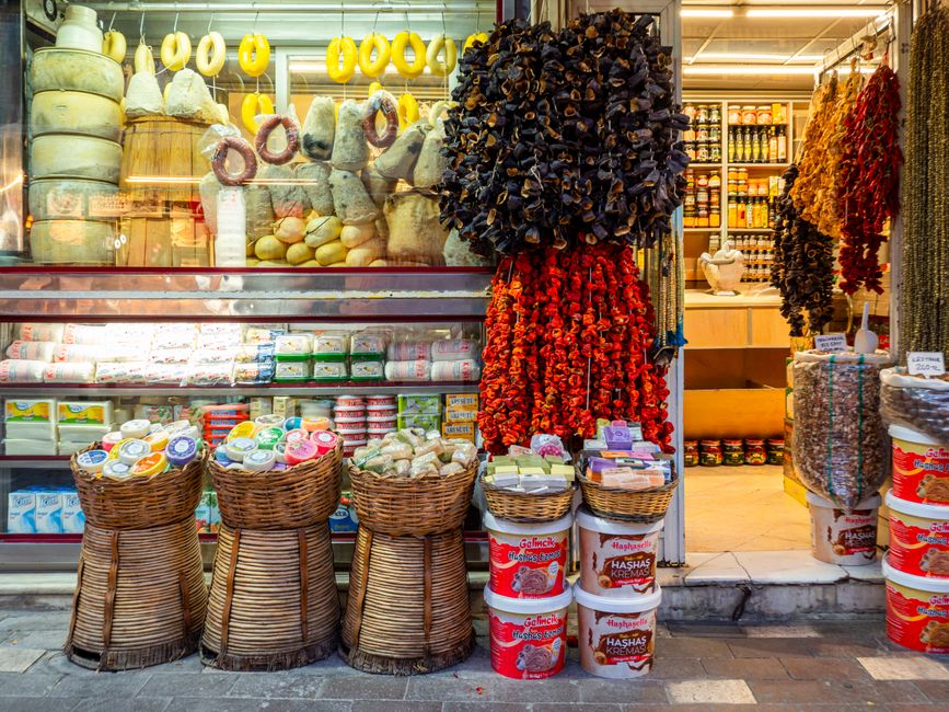 Bancarelle ricche e colorate in un vivace mercato alimentare europeo, con formaggi, frutta e verdura fresca in esposizione.