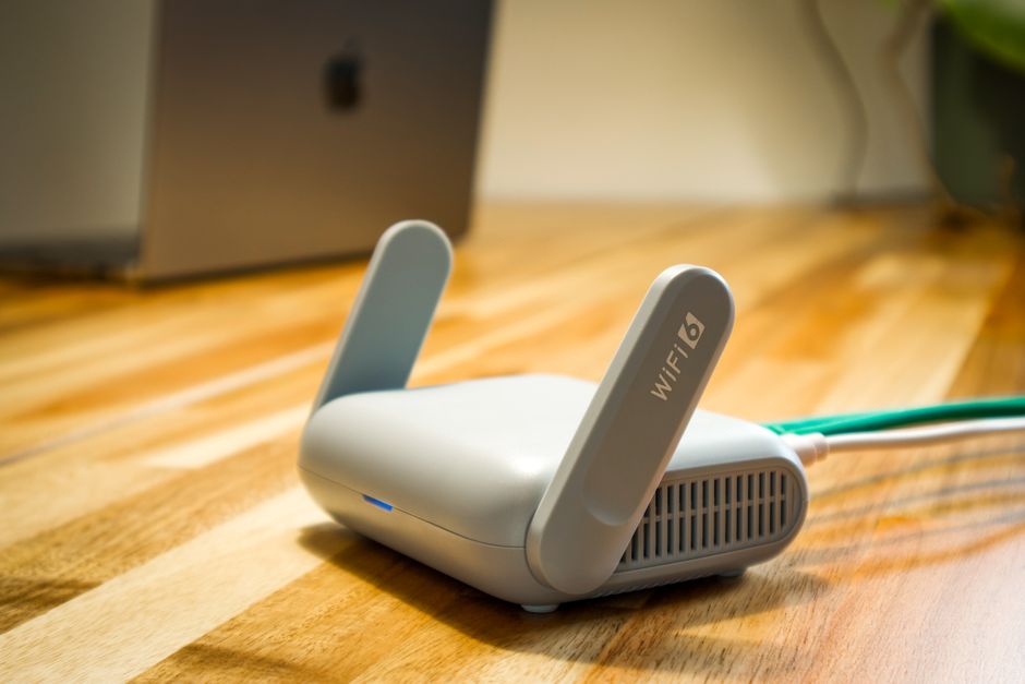 Un router Wi-Fi bianco posizionato su una mensola in un soggiorno luminoso con piante, ottimale per la diffusione del segnale.