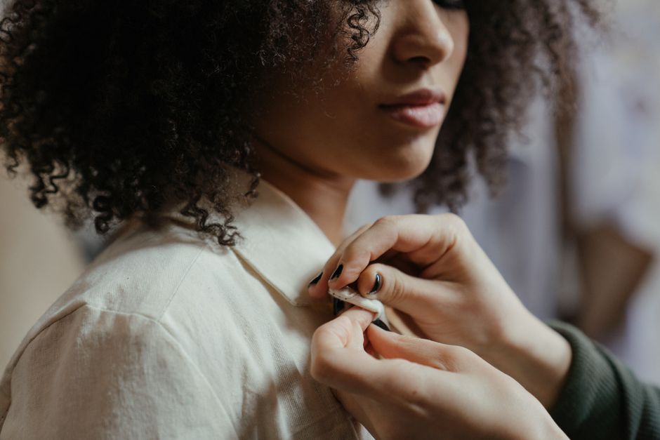 Una donna che si sistema la giacca sartoriale di colore neutro davanti a uno specchio, evidenziando la vestibilità perfetta del capo.
