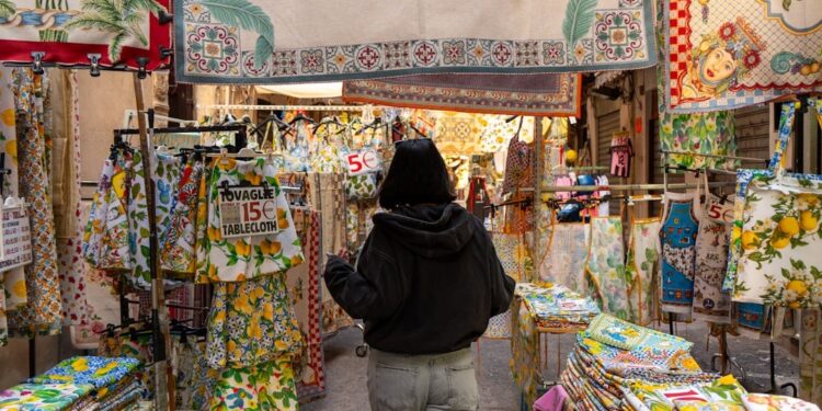 Donna italiana sorridente che sceglie verdure fresche al mercato all'aperto