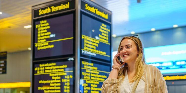 Donna che verifica i dettagli di un volo sul telefono con i suggerimenti dell'AI, con uno sfondo di viaggio