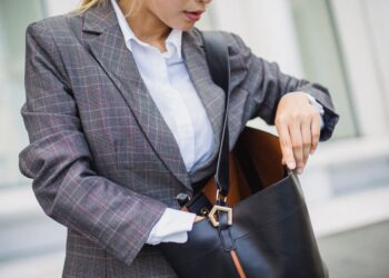 Donna che prova diversi abbinamenti di capi da ufficio e casual davanti a uno specchio, creando un look office casual.