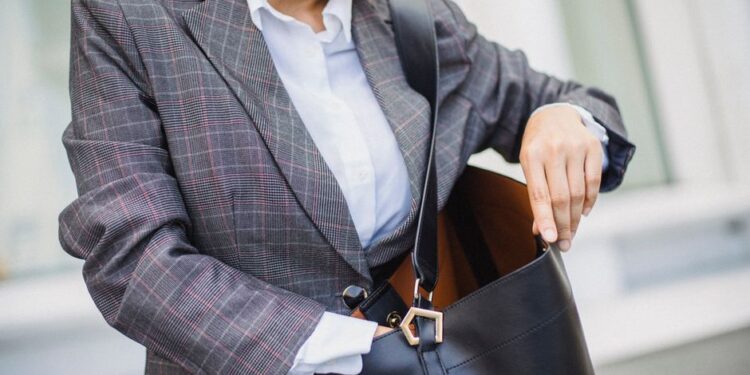 Donna che prova diversi abbinamenti di capi da ufficio e casual davanti a uno specchio, creando un look office casual.