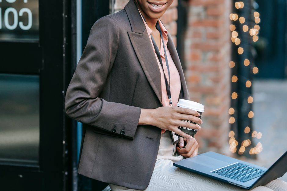 Donna al laptop con caffè, pronta per uscire a fare commissioni