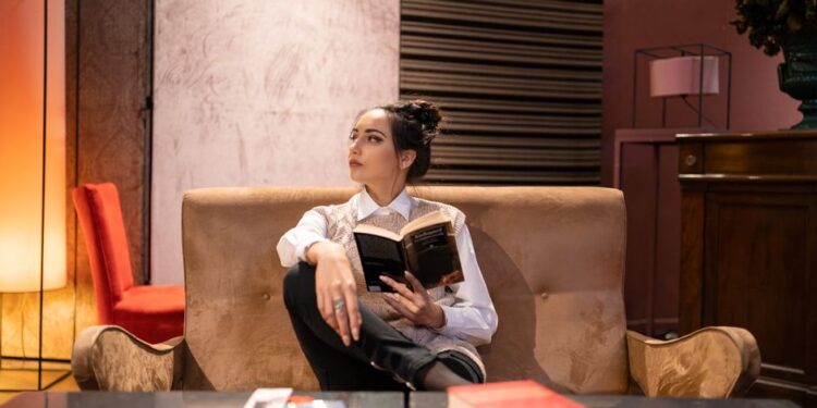 Жінка читає книгу на дивані під час короткої перерви в роботі вдома