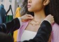 Donna che prova diverse combinazioni di accessori davanti a un armadio aperto, con un'espressione pensierosa ma creativa.