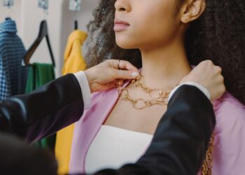 Donna che prova diverse combinazioni di accessori davanti a un armadio aperto, con un'espressione pensierosa ma creativa.