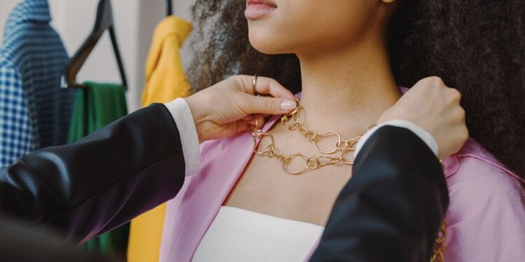 Donna che prova diverse combinazioni di accessori davanti a un armadio aperto, con un'espressione pensierosa ma creativa.
