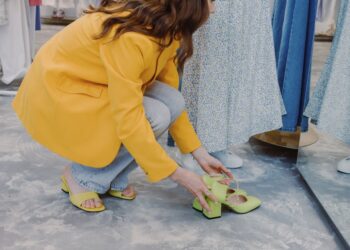 Donna prova eleganti scarpe da città in una boutique italiana, con un'ampia scelta in sottofondo